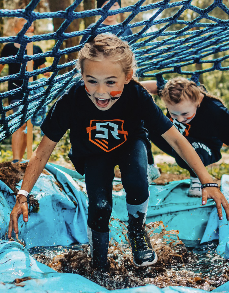 Dzieci pokonują przeszkodę w błocie. Survival Race Kids bieg z przeszkodami dla dzieci 2026